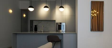 A modern kitchen with pendant lighting, a built-in microwave, and a bar stool.
