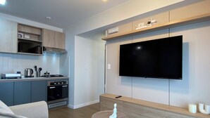 Una sala de estar moderna con un televisor de pantalla plana, una mesita redonda y un sofá.