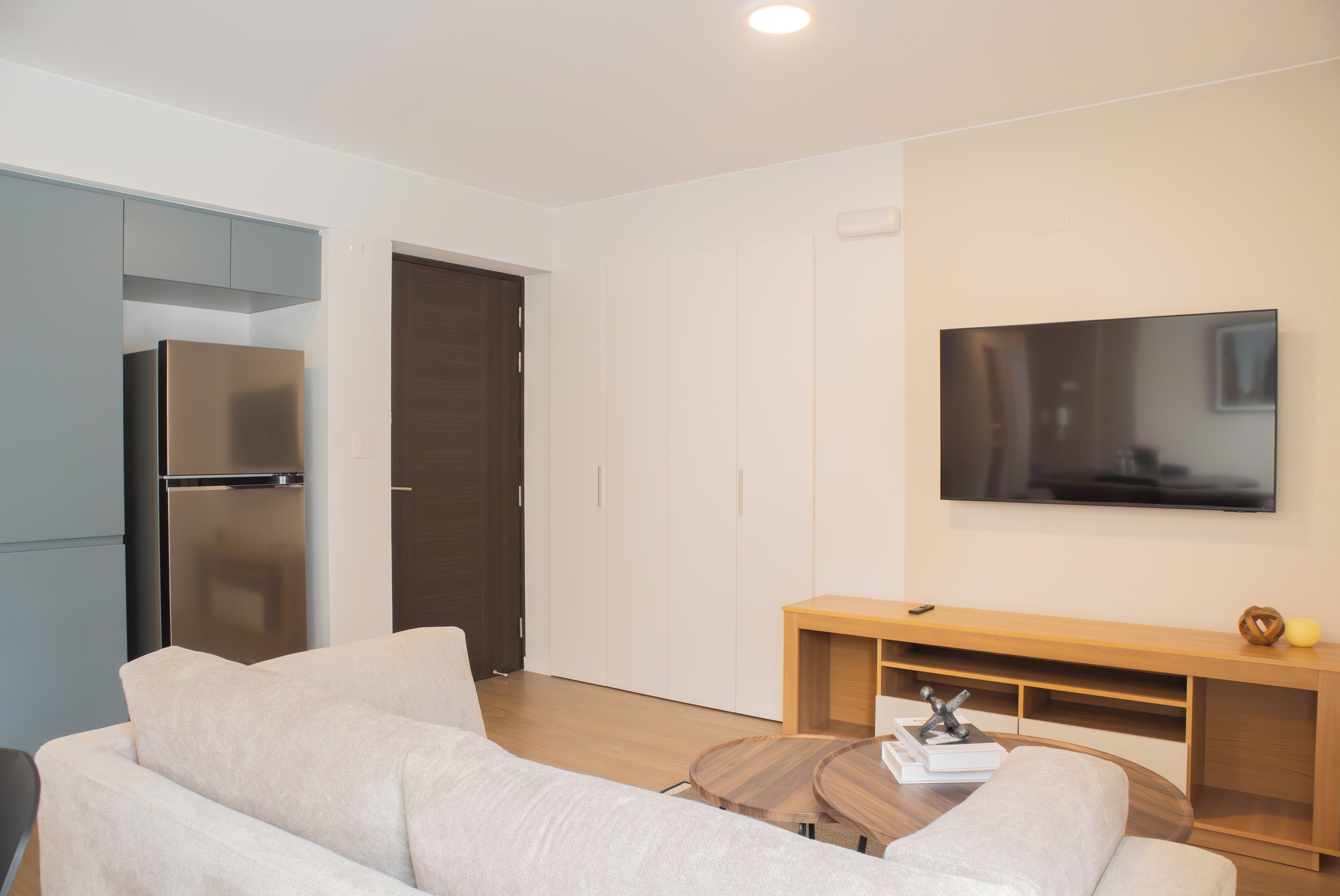 Un soggiorno moderno con un divano, un tavolino in legno, un televisore a schermo piatto e un mobile porta TV integrato in legno.