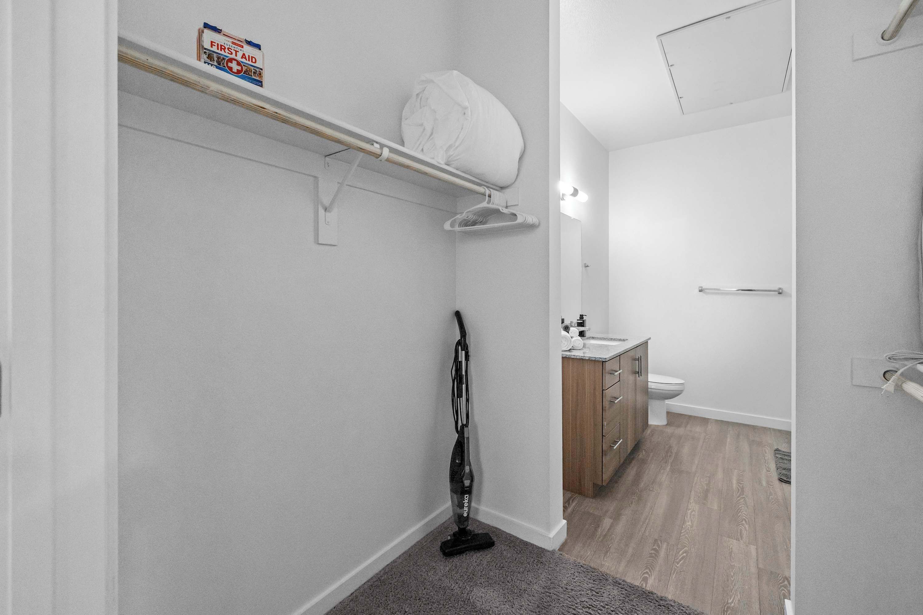 A clean, modern bathroom with a toilet, sink, and a vacuum cleaner.
