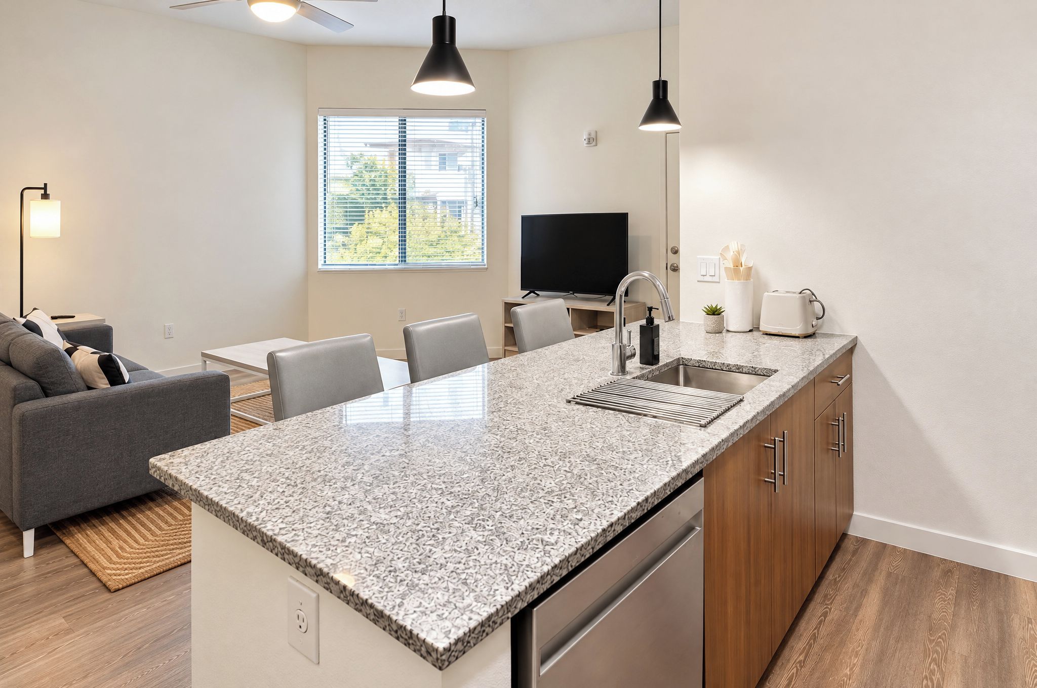 A modern kitchen with a granite countertop, wooden cabinets, and a built-in dishwasher.