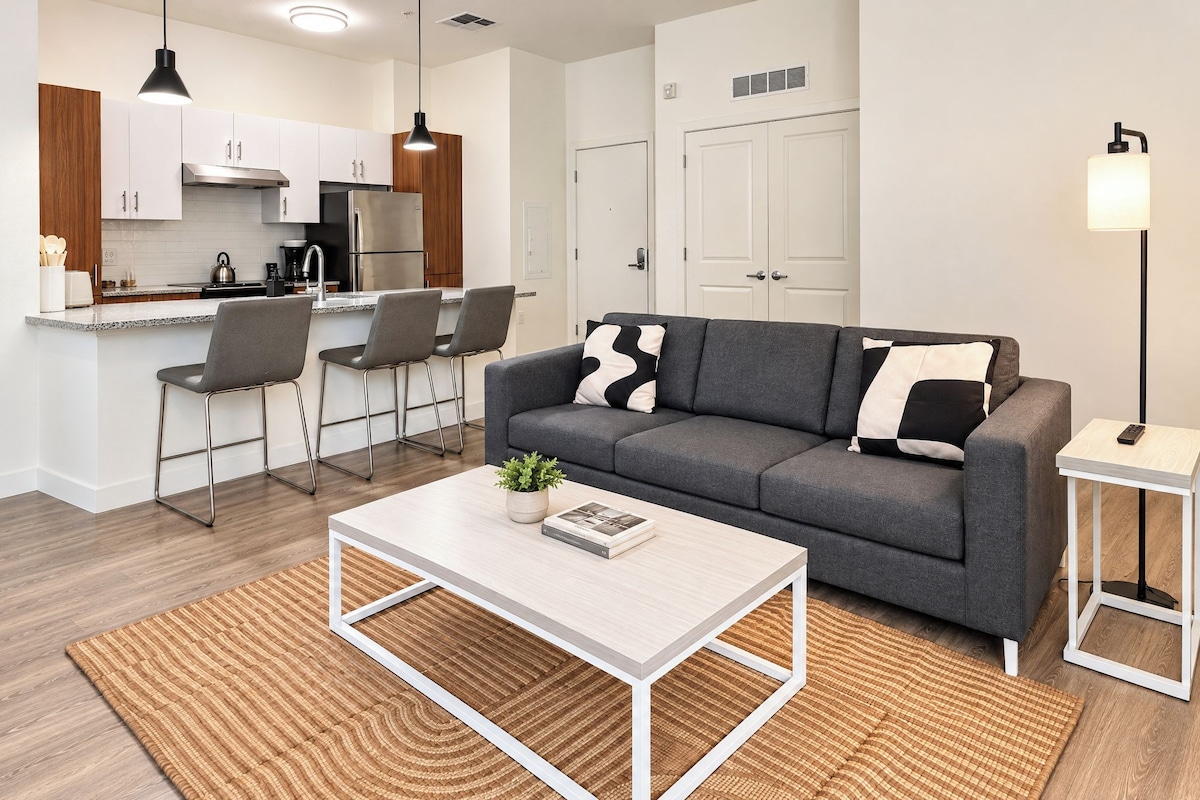 A modern living room with a grey sofa, a coffee table, and a small side table.