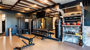 Un gimnasio moderno con diferentes equipos de ejercicio, incluyendo mancuernas, kettlebells y un saco de boxeo.