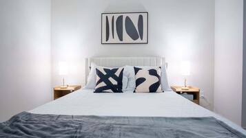A neatly made bed with a white headboard and two bedside tables, each with a lamp.