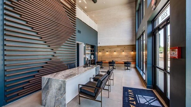 Un área de recepción moderna con un revestimiento de listones de madera, una encimera de mármol y asientos.