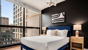 A modern bedroom with a large bed, two bedside tables, and a city view. - Boulevard Stays - River North (Chicago)