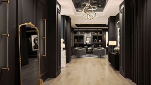 A hallway with a mirror, two armchairs, a chandelier, and a bookshelf. - Boulevard Stays - River North (Chicago)
