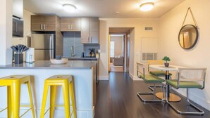 A modern kitchen with stainless steel appliances, a central island with stools, and a dining area with a round table and chairs. - Boulevard Stays - Ladybird Lake (Austin)