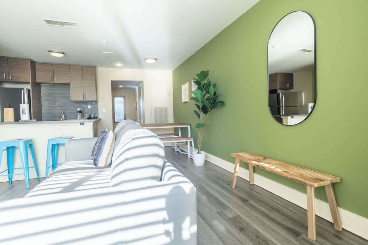A modern living room with a sofa, a bench, and a dining area with stools.