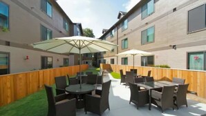 An outdoor patio area with tables and chairs, surrounded by wooden fencing and a grassy lawn. - Boulevard Stays - Ladybird Lake (Austin)