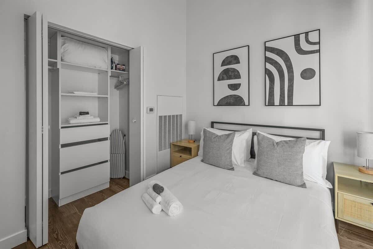 Une chambre d’hôtel comprenant un lit, une armoire et deux œuvres d’art abstraites accrochées au mur.