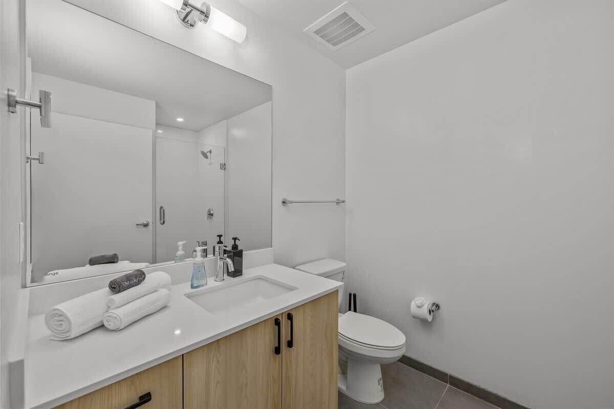 Un baño moderno con un espejo grande, un lavabo, un inodoro y una zona de ducha.