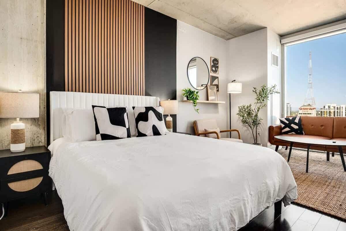 A modern hotel room with a large bed, a round coffee table, a sofa, and a view of a tower.