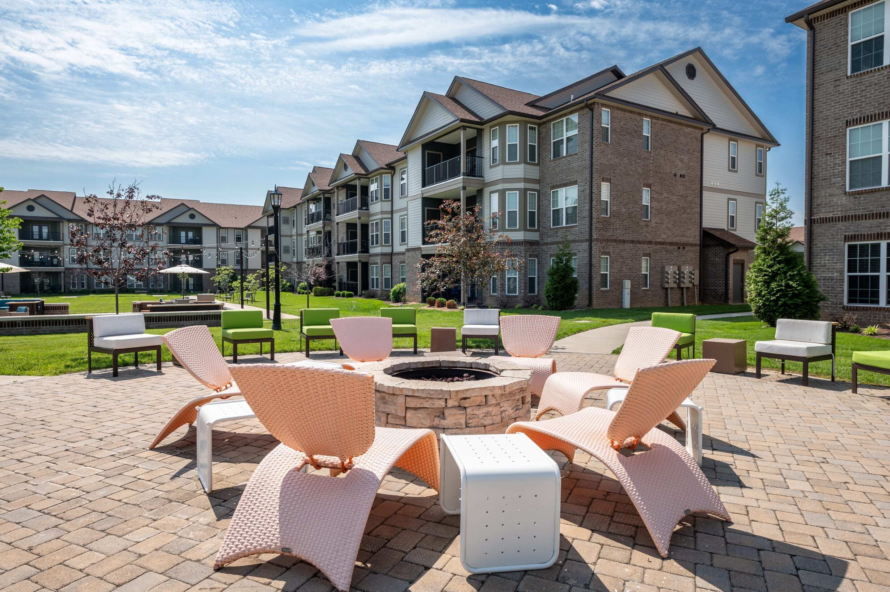 A courtyard with outdoor seating, a fire pit, and a brick building with multiple balconies.