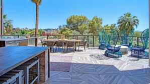 An outdoor patio with a table and chairs, a patterned floor, and a view of trees and buildings. - Boulevard Stays - Roosevelt Row (Phoenix)