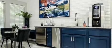 A modern kitchen with a blue island, stainless steel appliances, and a large abstract painting on the wall.