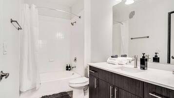 A modern bathroom with a bathtub, toilet, and vanity with a mirror.