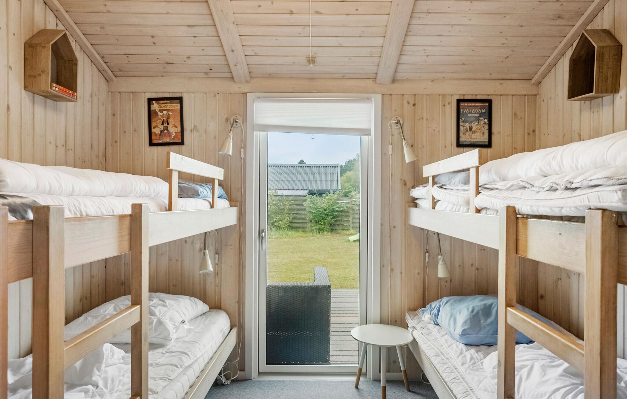 A cabin with bunk beds, a small table, and a door leading to an outdoor area.