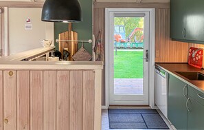A compact kitchen with a wooden countertop, a black pendant light, and a door leading to a green lawn. - Cozy home in Væggerløse with sauna (Væggerløse)