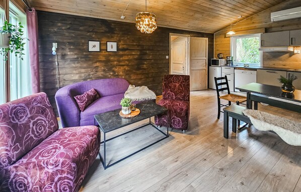 A cozy living room with a purple sofa, a coffee table, and a dining area with a table and chairs. - Awesome home in Røldal with WiFi (Røldal)