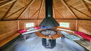 A wooden attic room with a central fireplace, two windows, and a sloped ceiling. - Awesome home in Røldal with WiFi (Røldal)