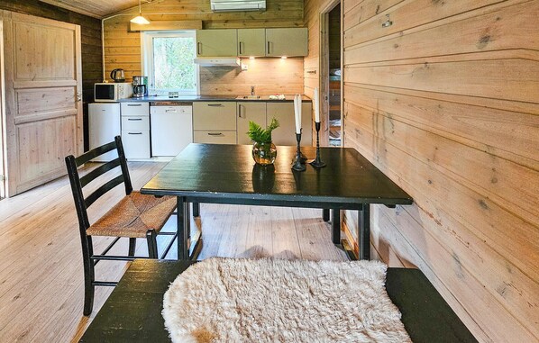 Un intérieur en bois comprenant une table à manger, des chaises, une petite plante et un tapis.