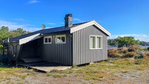 A small, single-story cabin with a sloped roof, a chimney, and a small porch. - Awesome home in Kolbjørnsvik with house sea view (Kolbjørnsvik)