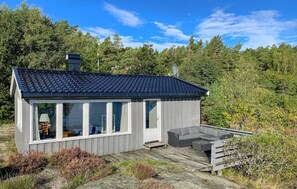 A small wooden cabin with a tiled roof, large windows, and a deck with outdoor furniture. - Awesome home in Kolbjørnsvik with house sea view (Kolbjørnsvik)