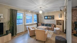 A cozy living room with a sofa, chairs, a coffee table, a TV, and a fireplace. - Cozy home in Flekkefjord with house sea view (Flekkefjord)