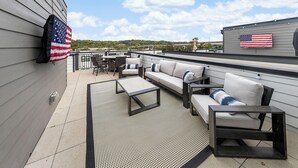 A rooftop patio with a sofa set, a coffee table, and an American flag.