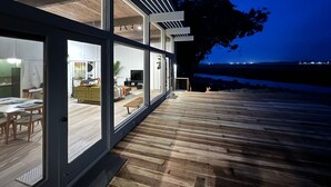 Ein modernes Haus mit großen Glasüren, die in einen Essbereich und ein Wohnzimmer führen.
