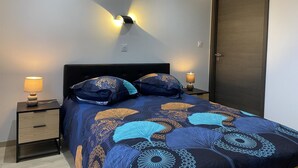 A bedroom with a bed, two bedside lamps, a dark door, and a wall-mounted light fixture. - GITE DE L'ETOILE - ROCROI (ROCROI)