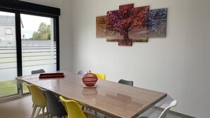 A dining area with a long table, colorful chairs, and a large window. - GITE DE L'ETOILE - ROCROI (ROCROI)