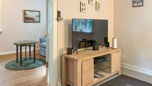 Un saló amb un moble de comunicació de fusta, una televisió de pantalla plana, una taula auxiliar petita i un sofà blau.