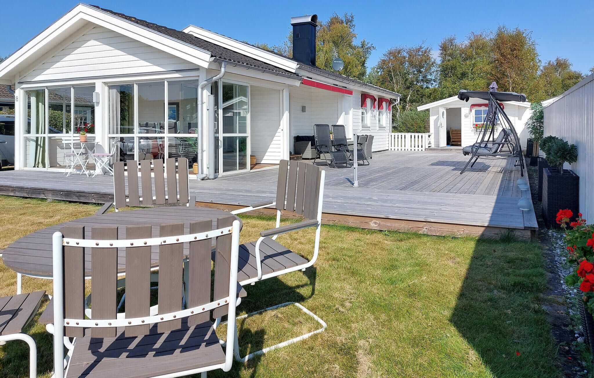 A modern house with a covered patio, outdoor seating, and a well-maintained lawn.