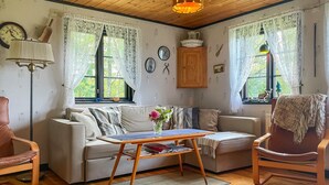 A cozy living room with a sofa, a small table with a vase of flowers, and a wooden floor.