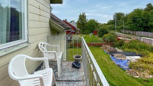 Een balkon met twee witte plastic stoelen, een bloempot en een tafeltje.