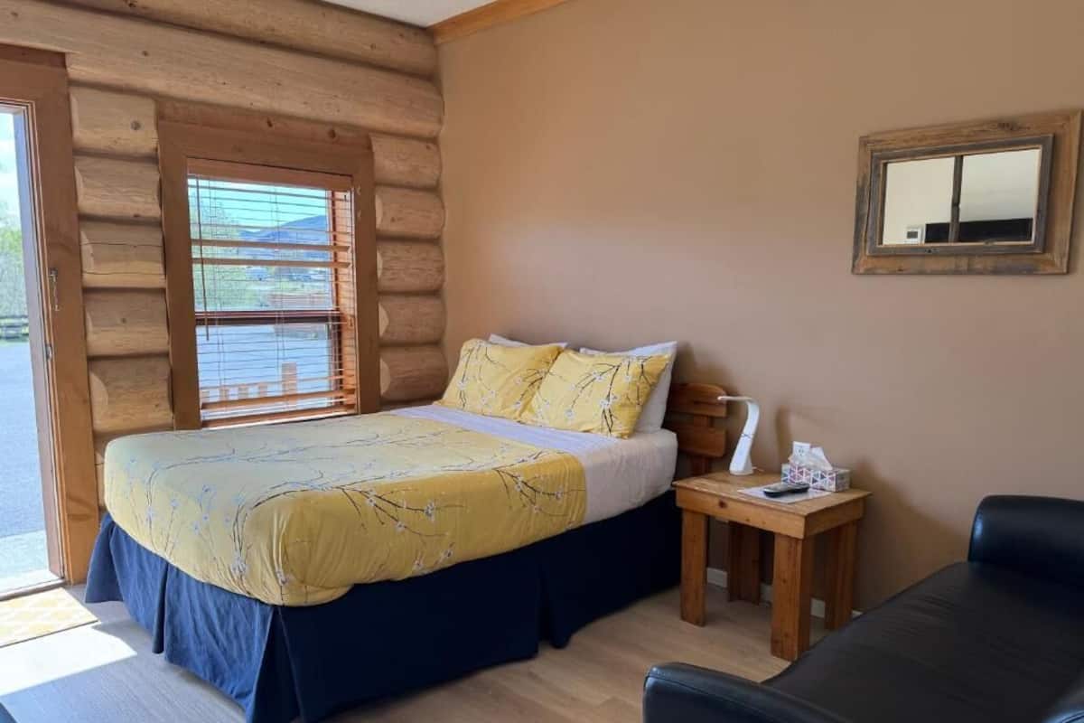 A log cabin-style room with a bed, bedside table, and a chair.