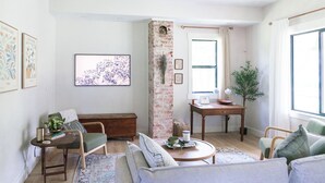 Una sala de estar acogedora con pared de ladrillo, un sofá, una mesa de centro y una estantería.