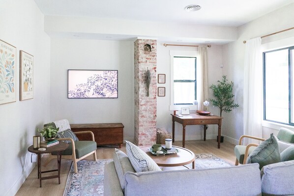 A cozy living room with a brick wall, a sofa, a coffee table, and a bookshelf.