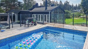 Una piscina amb una zona de bar flotant, envoltada per un solàrium i un porxo amb finestres.