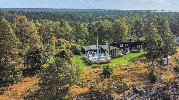 Una casa moderna amb piscina, envoltada per un bosc dens.