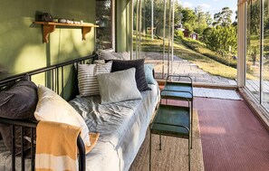 A cozy room with a sofa, pillows, a small table, and a view of a green landscape through large windows. - Pet friendly home in Vätö with sauna (Vätö)