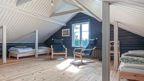 Une chambre mansardée chaleureuse, avec un plafond en pente, une grande fenêtre et un plancher en bois.