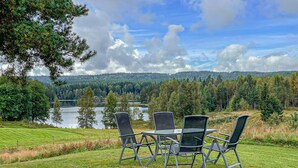 Un coin repas avec une table et des chaises donnant sur un lac et une forêt.