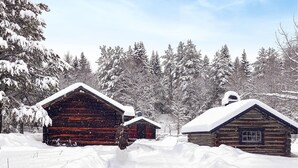 Een houten blokhut omringd door sneeuwbedekte bomen.