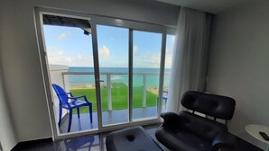 A modern room with a large sliding glass door leading to a balcony with a view of the sea. - Vila Mar Hotel (Olinda)