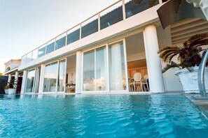 Un hotel moderno con una piscina grande, ventanas amplias y un balcón.