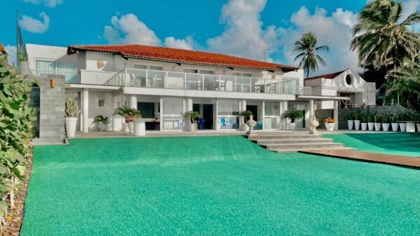 Un hotel moderno con una amplia piscina, un espacio exterior cubierto y una estructura de dos pisos.