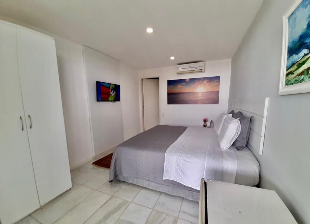 Een slaapkamer met een bed, een kledingkast, een schilderij en een airconditioning.
